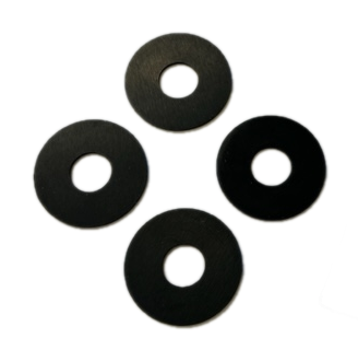 The image depicts four black, ring-shaped objects with a cross-shaped indentation in the center. The objects are laying flat on a light gray, textured surface. They are commonly referred to as plunger washers.