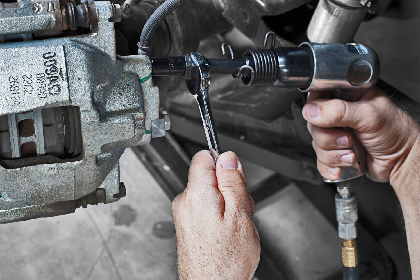 the image shows that someone is using an impact drill and open wrench to remove a screw.