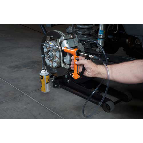 The image shows a mechanic using a brake fluid bleeding gun to bleed a brake caliper on a car.