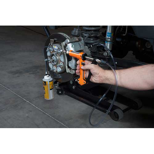 The image shows a mechanic using a brake fluid bleeding gun to bleed a brake caliper on a car.