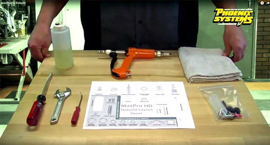 The picture depicts a table with tools including a screwdriver, wrench, and bleeding kit. It also has a document labeled "MaxProHD Rebuild Layout Sheet," which is a parts diagram rather than a picture. It shows several pieces arranged on a table, maybe for a machine. 